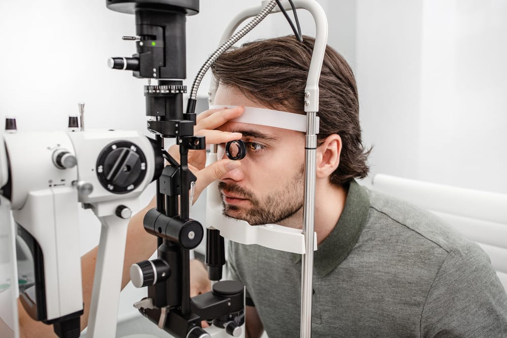 Man receiving a detailed slit lamp eye examination, used by optometrists to detect vision problems and assess eye health conditions.