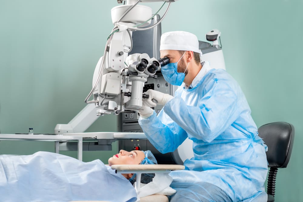 Surgeon using an operating microscope to perform delicate eye surgery, demonstrating expert care in a sterile surgical environment.